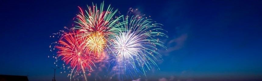 Multiple colorful aerial fireworks exploding against a dark skyline.