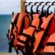 orange life jackets hanging on a rack in front of an ocean view