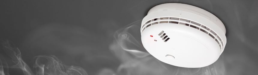 smoke alarm mounted to a ceiling surrounded by smoke
