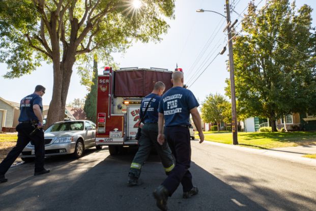 three firefighters walking behind a fire engine