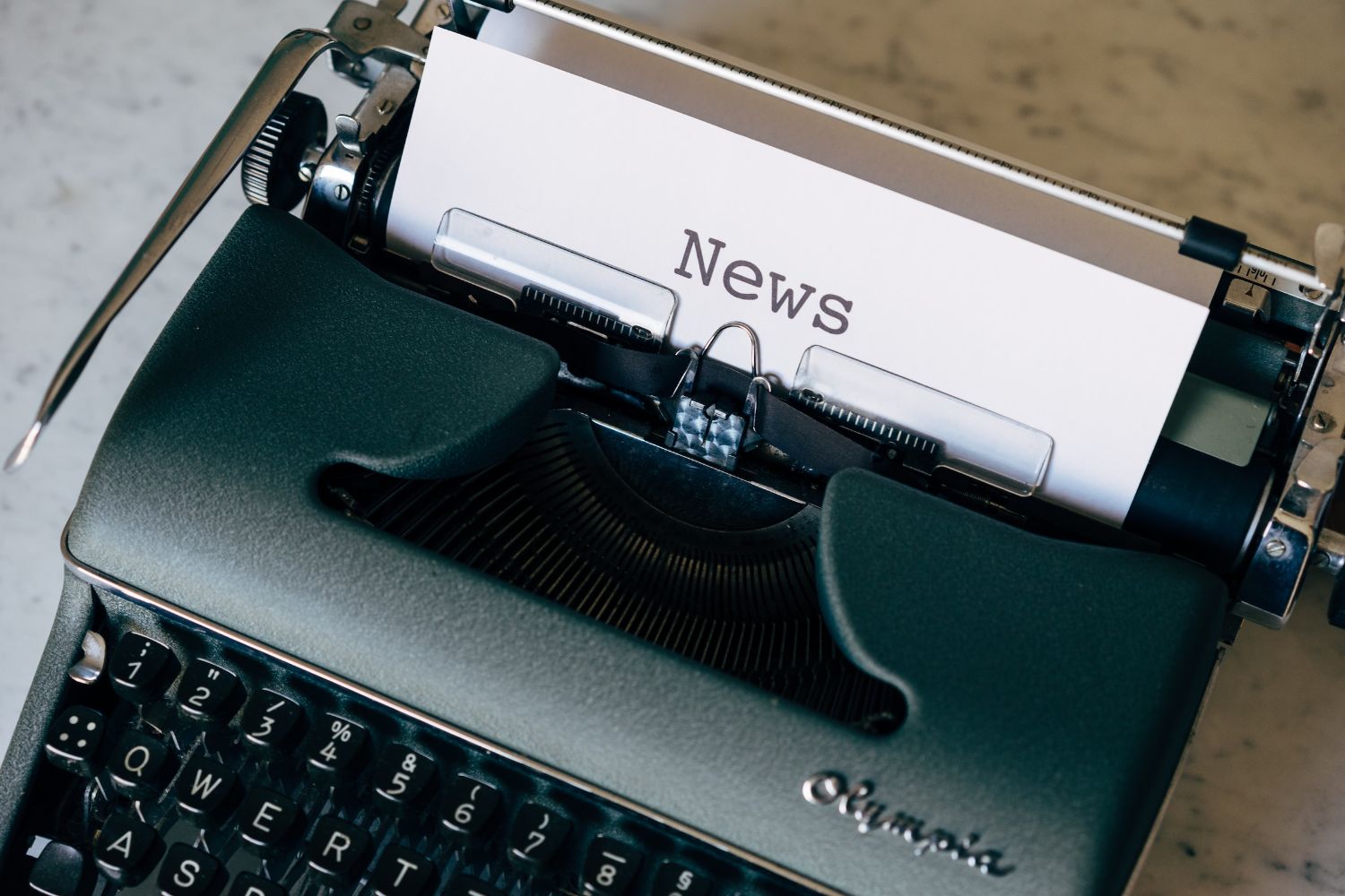 type writer with a white page that reads News