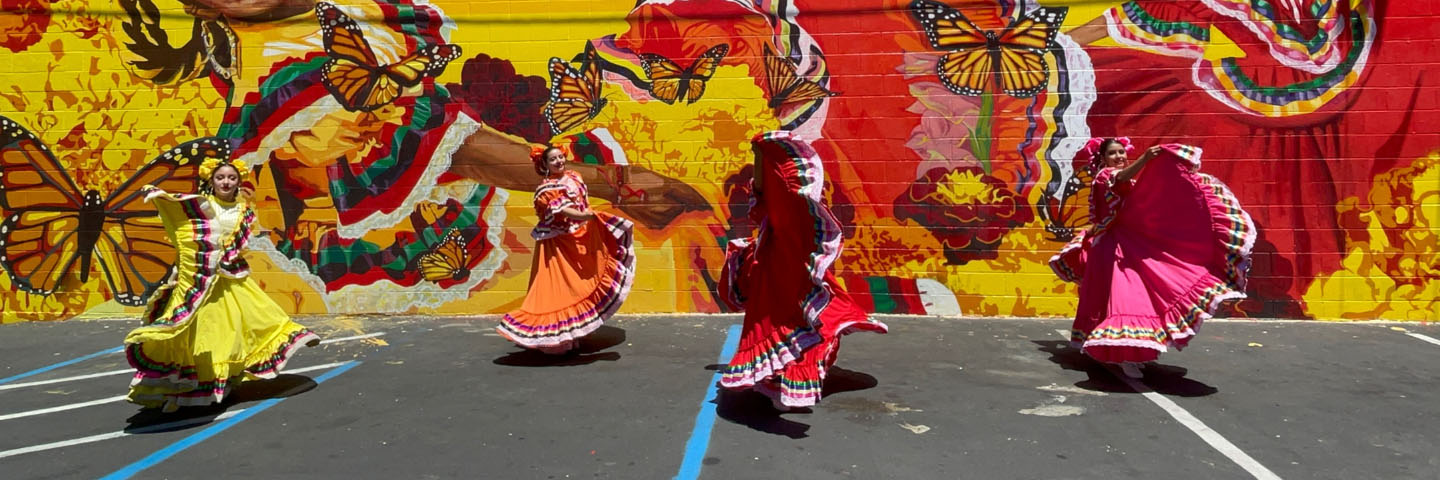 Four dancers in front of a mural