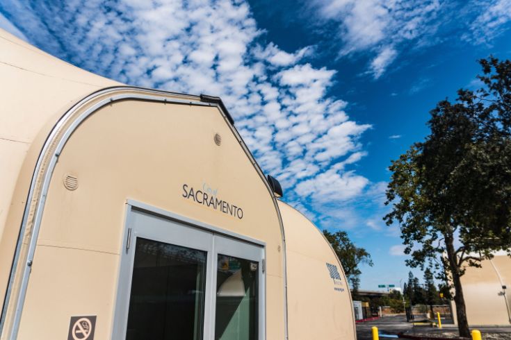 X Street Shelter, tan building with the City logo, clouds, tree