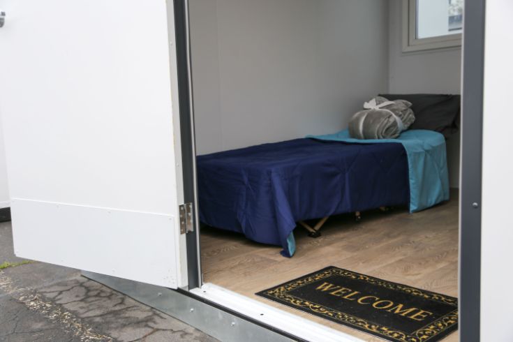 Inside Roseville Road tiny home, bed, pillow, blankets, welcome mat