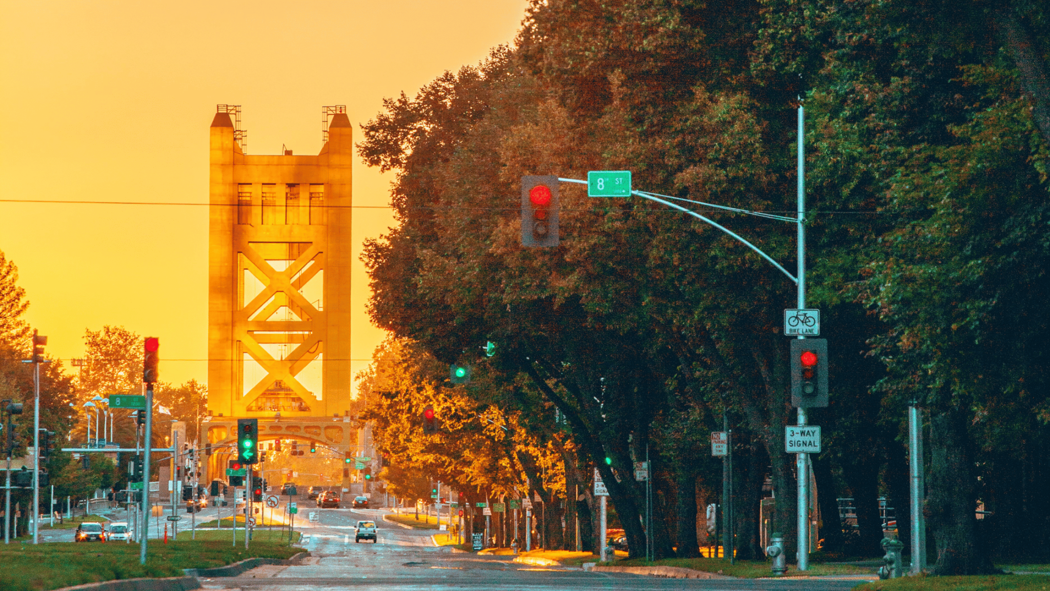 Yellow Tower Bridge in Sacramento with a red traffic light and an 8th Street sign in the foreground,