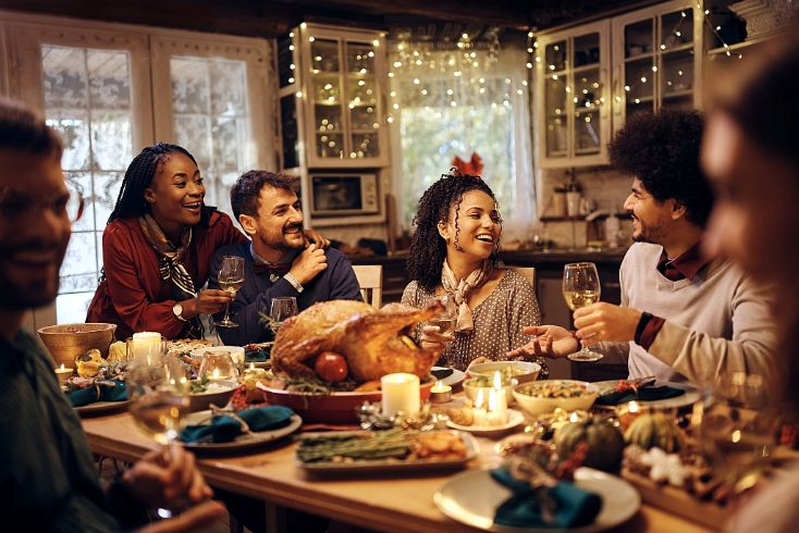 People surrounding a dinner table for Thanksgiving
