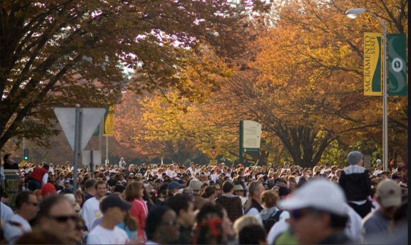 Crowds of people at a marathon, fall trees