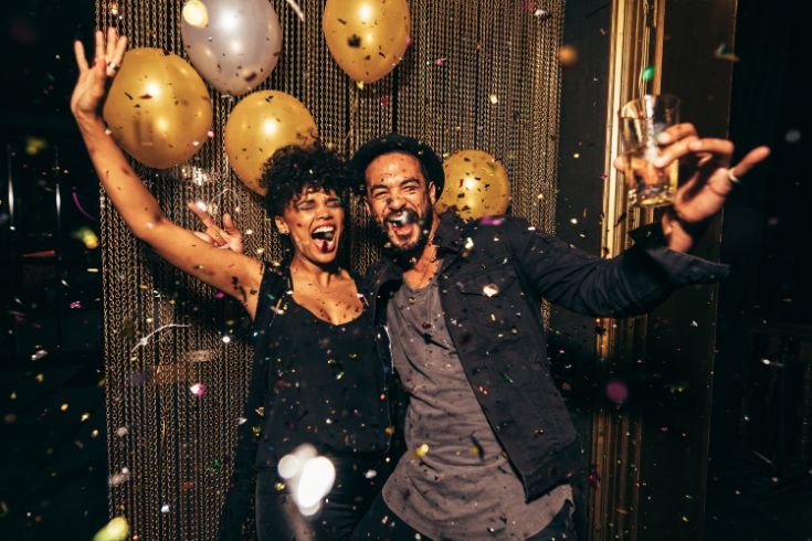 Two people celebrating at a club. Confetti and balloons