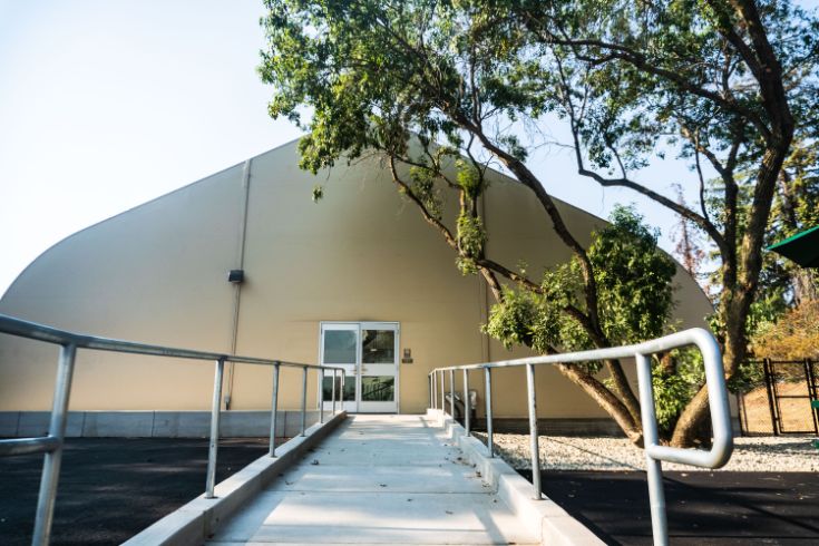 tan building with accessibility ramp, tree