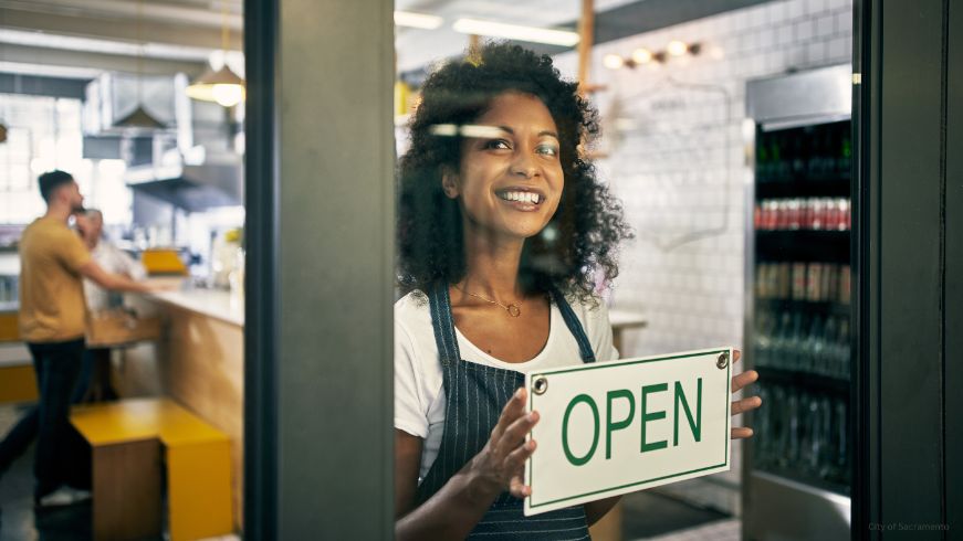 Person switching business sign to "Open"