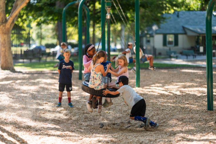 Kids playing on a park tire swing