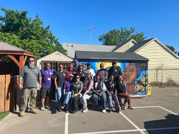 Large group photo in front of mural