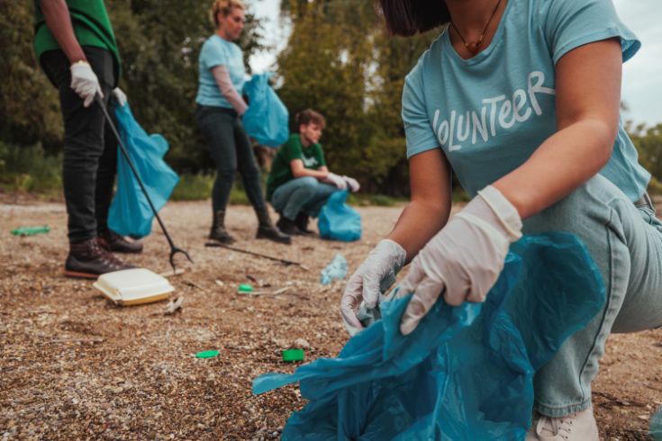 Volunteers picking up trash wearing gloves and holding trash bags