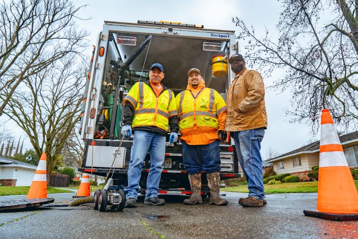 Three Department of Utilities staff members standing  in front of truck