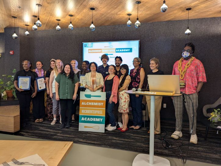 Large group photo behind sign that says "Alechemist Microenterprise Academy"