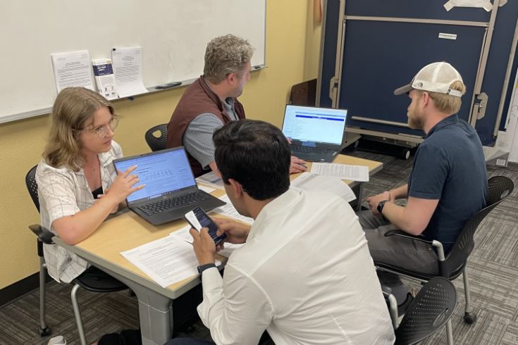 Group sitting at a table working on laptop and smart phones.