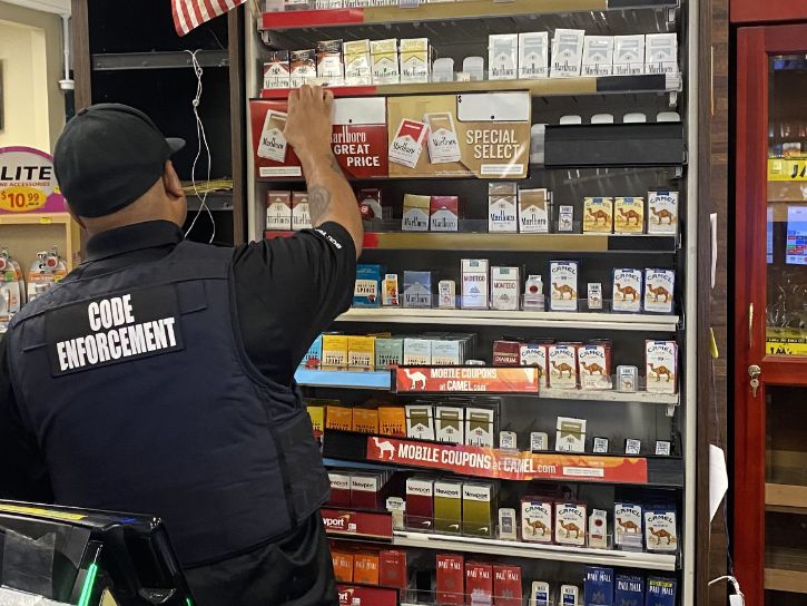 Code Enforcement Officer going through tobacco products at store.