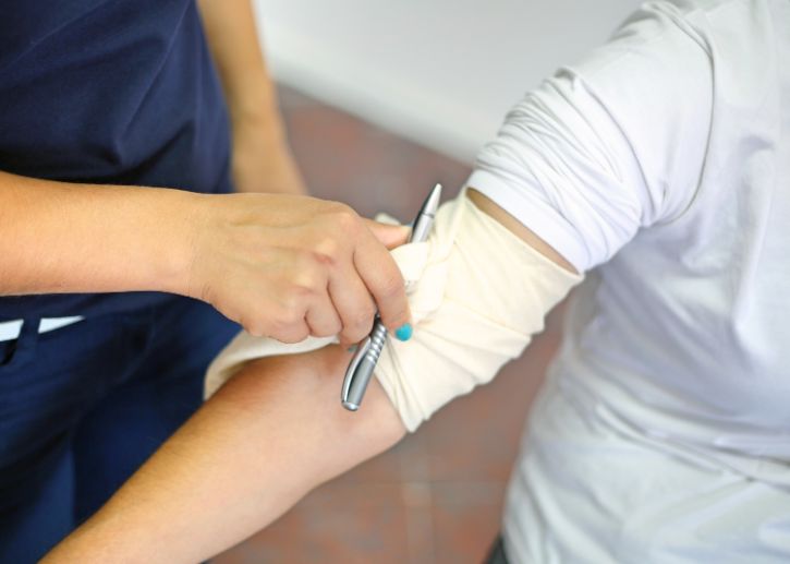 Person applying bandage to another person's arm