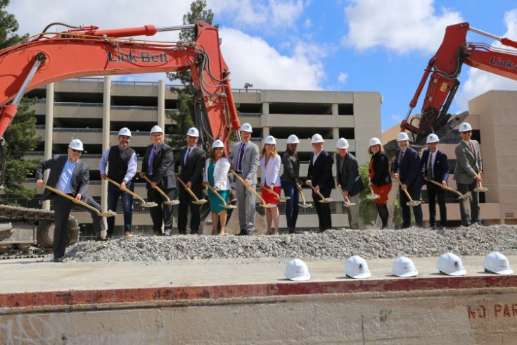 Construction site, group photo of people wearing hardhats and holding golden shovels