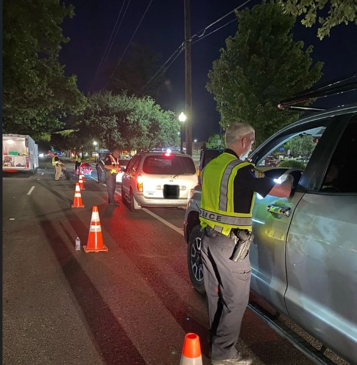 DUI checkpoint. Police speaking to people at their cars, orange cones