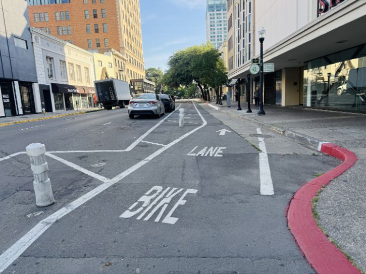 Bike lane, red curb, sidewalk, city buildings