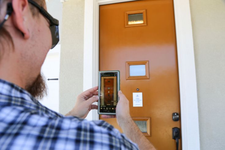 Person holding phone up filming door for virtual inspection