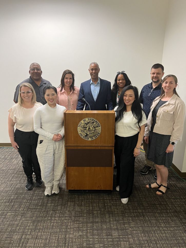 9 people standing at podium for a group photo