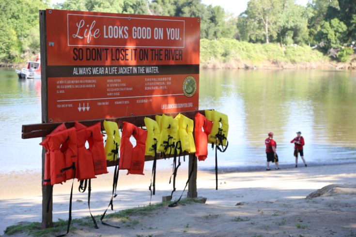 Life jackets, two people standing by the river