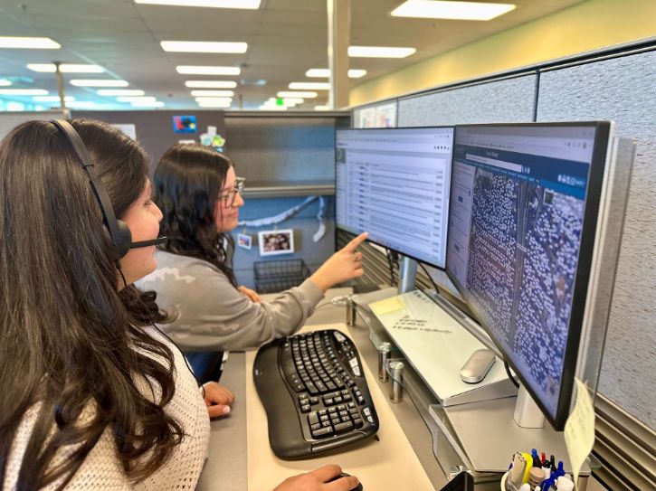 Two people working on a computer. One person pointing at the screen.