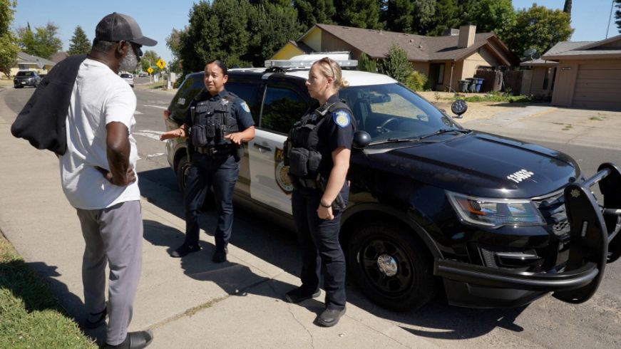 Two officers speaking to person on a sidewalk