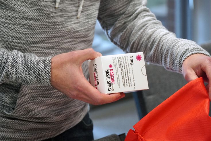 Person holding box that says "Narcan Nasal Spray"