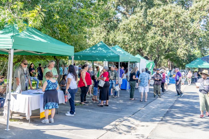 Tabling event, crowd, green shade cover, trees