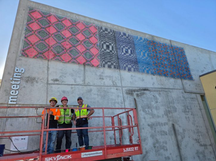 Mural, three people smiling for camera wearing hard hats