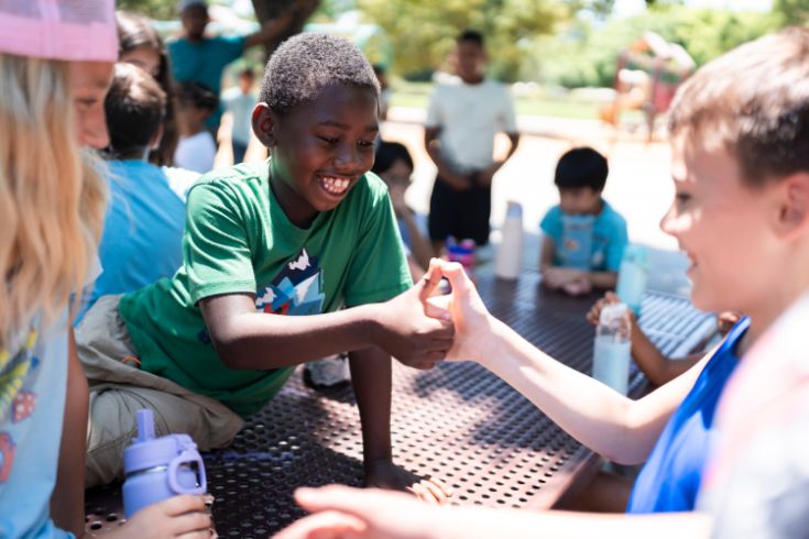 Two kids playing the game thumb war and smiling