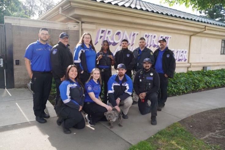 Group photo with dog in the center outside of Front Street Animal Shelter.