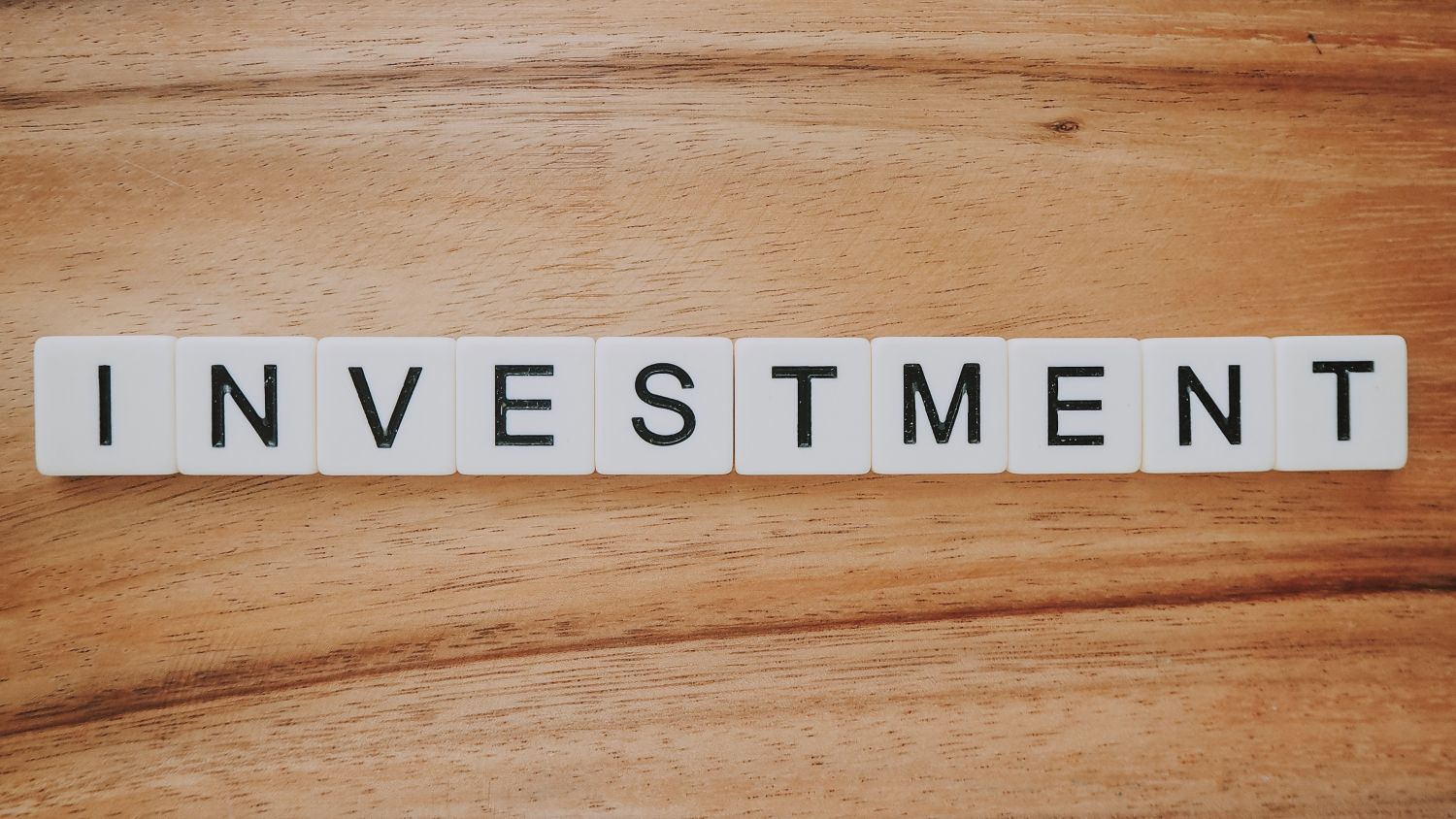 White square tiles with black lettering that spell out the word investing