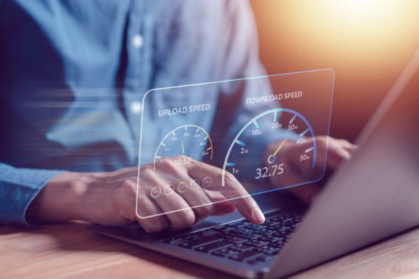 An image of a person typing on a laptop with speed test meter