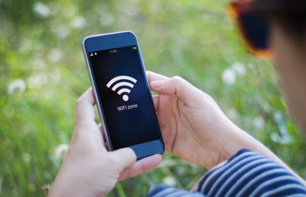 Person with cell phone outdoors with Wi-Fi signal showing