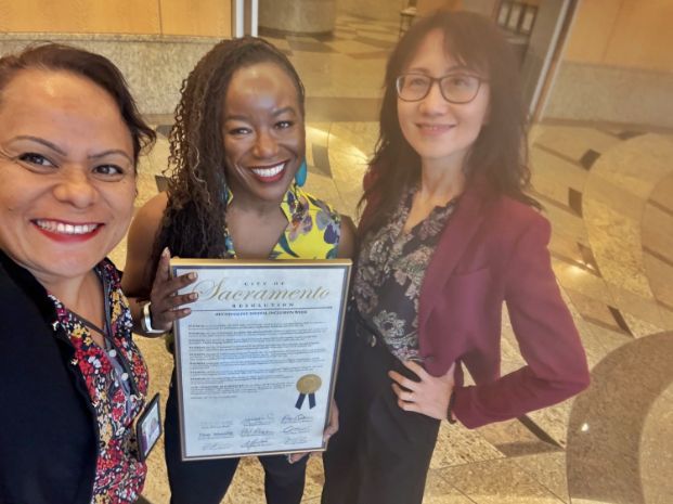 Photo of three IT staff members holding City-issued resolution for Digital Inclusion Week