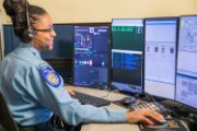 A photo of a Sacramento Police Department Dispatcher sitting at their workstation, with multiple screens mounted in front of them