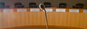 A photo of the microphone in Sacramento City Council Chambers, with the wooden planked dais and council members' chairs in the background