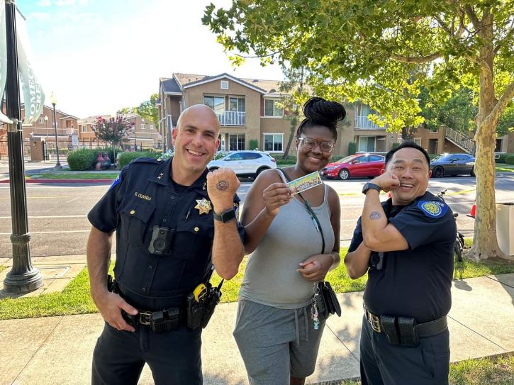 A photo of Deputy Chiefs Oliviera and Leong standing to either side of a community member at a National Night Out event