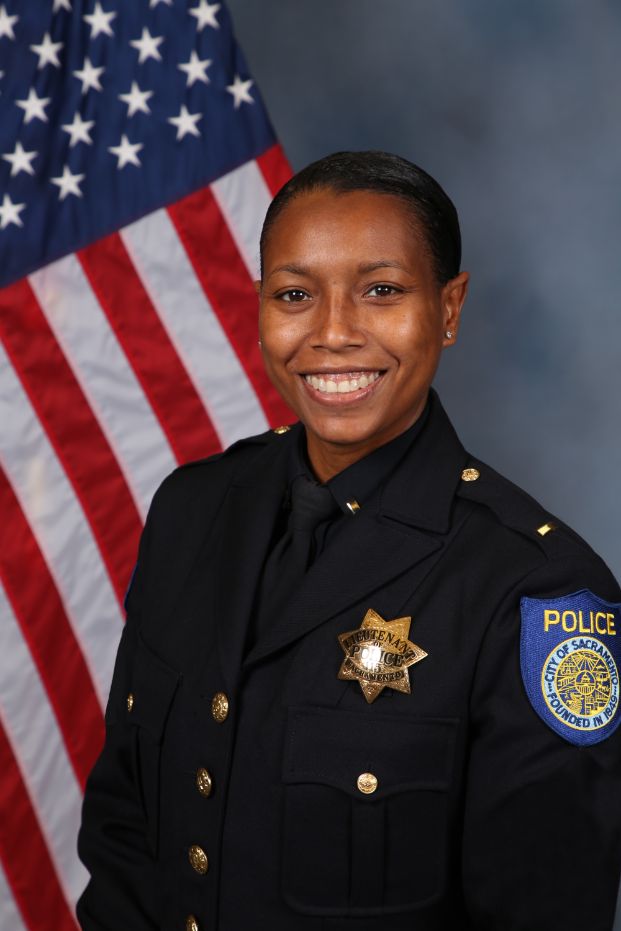 Photo of Sabrina Briggs in uniform standing in front of the American flag.