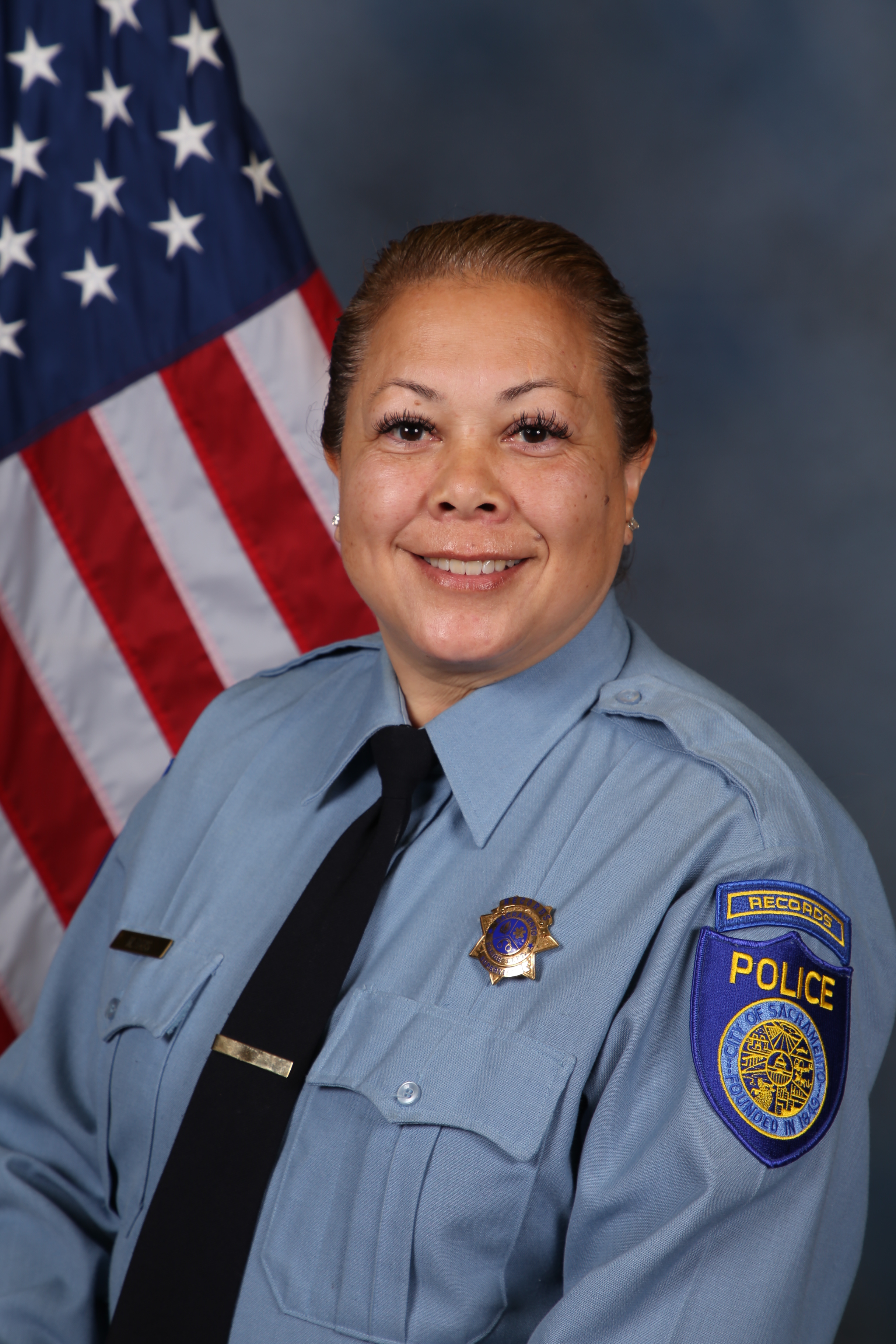 Photo of Michelle Bays in uniform standing in front of the American flag.