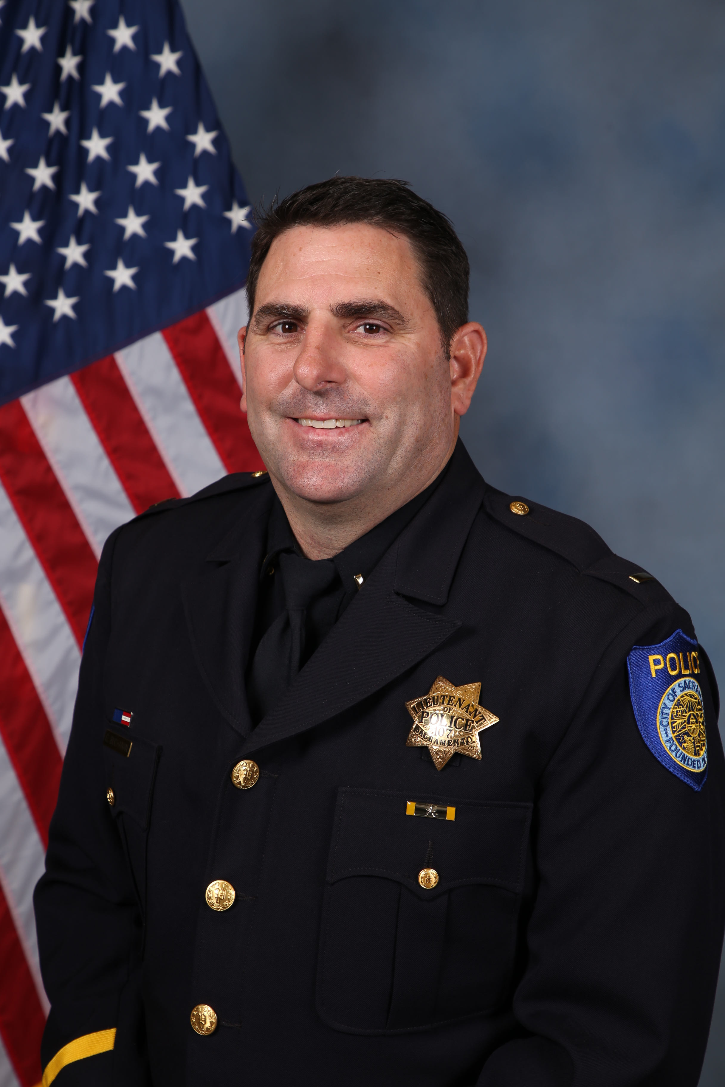 Photo of Clayton Buchanan in uniform standing in front of the American flag.