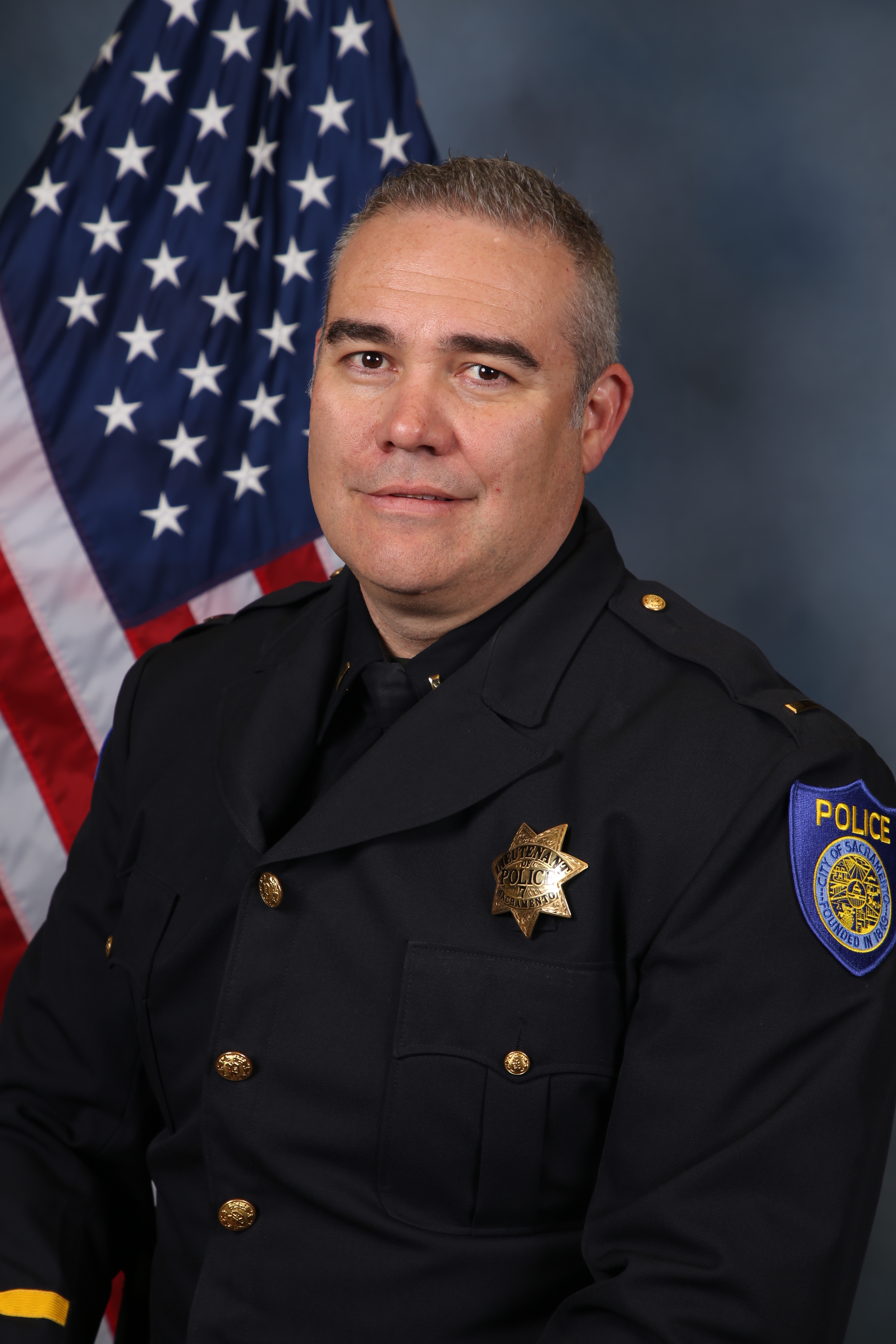 Photo of Ryan Bullard in uniform standing in front of the American flag.