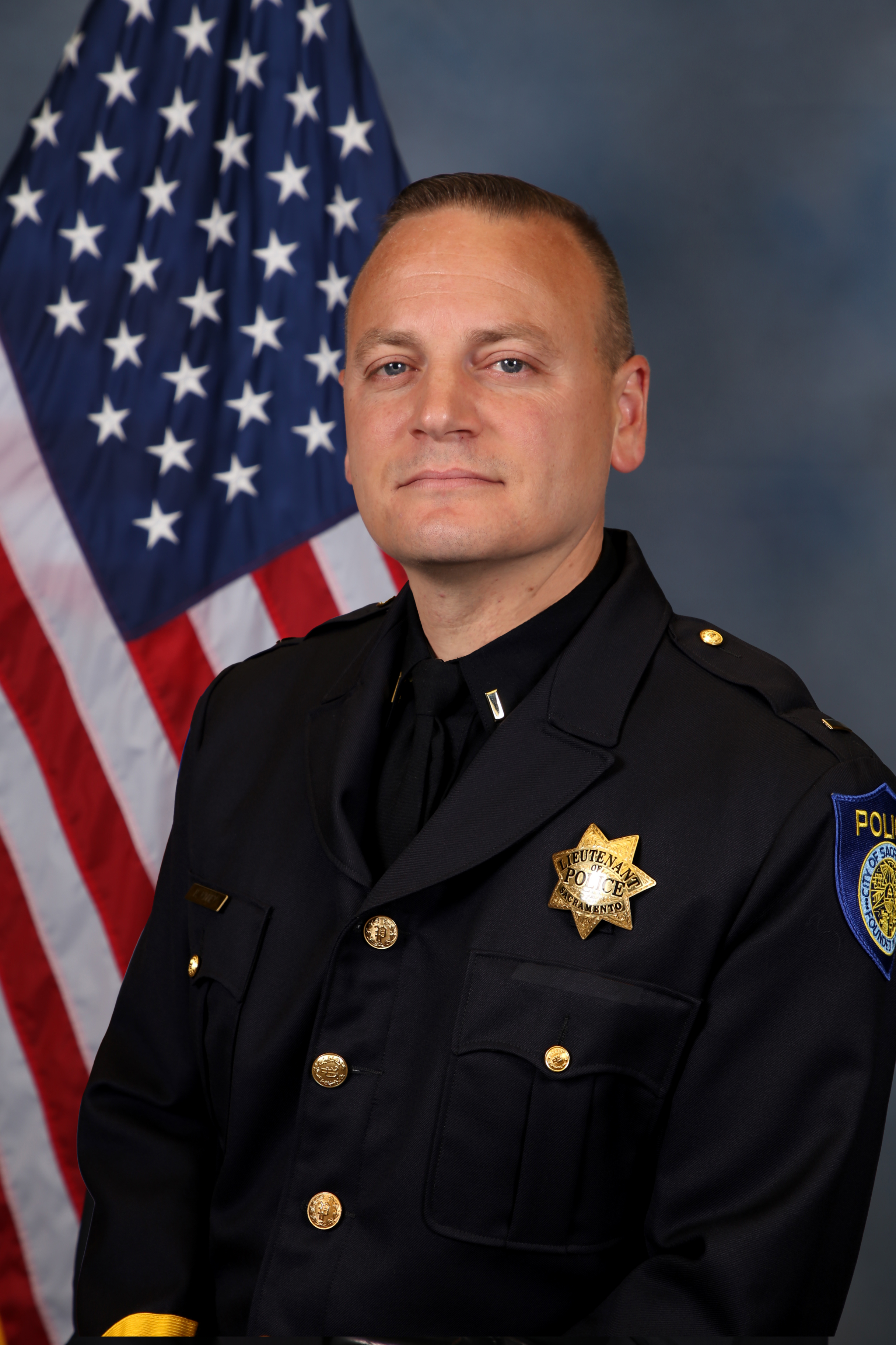 Photo of Will Conner in uniform standing in front of the American flag.