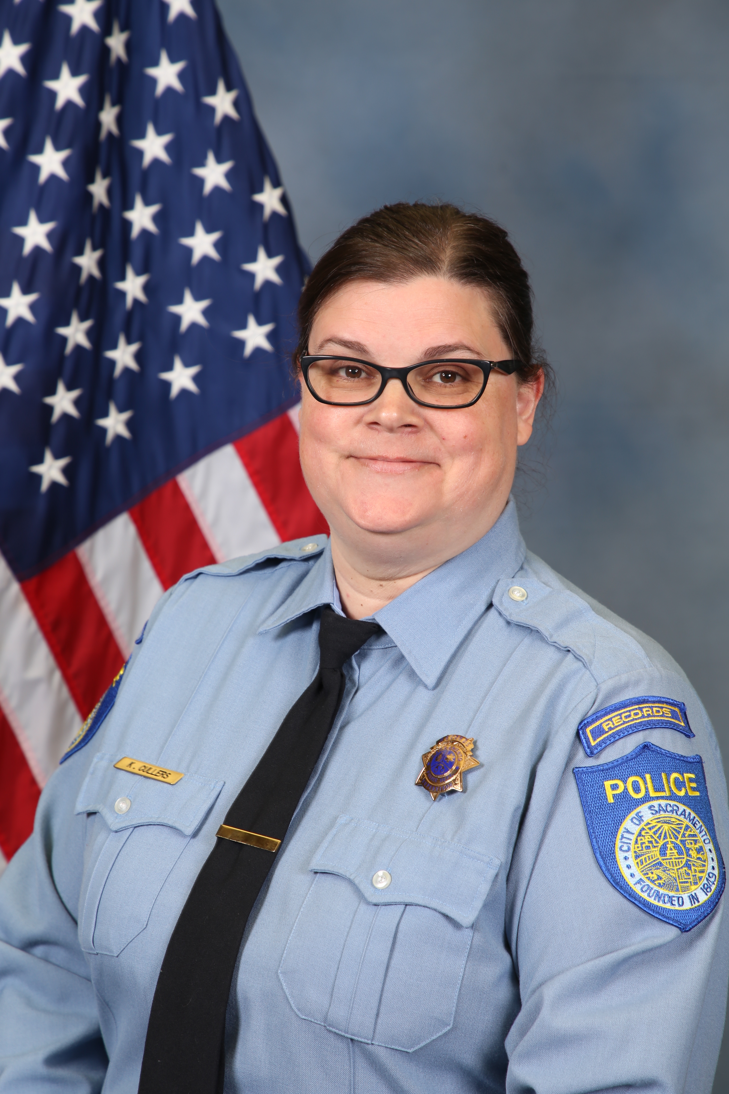 Photo of Kelly Cullers in uniform standing in front of the American flag.