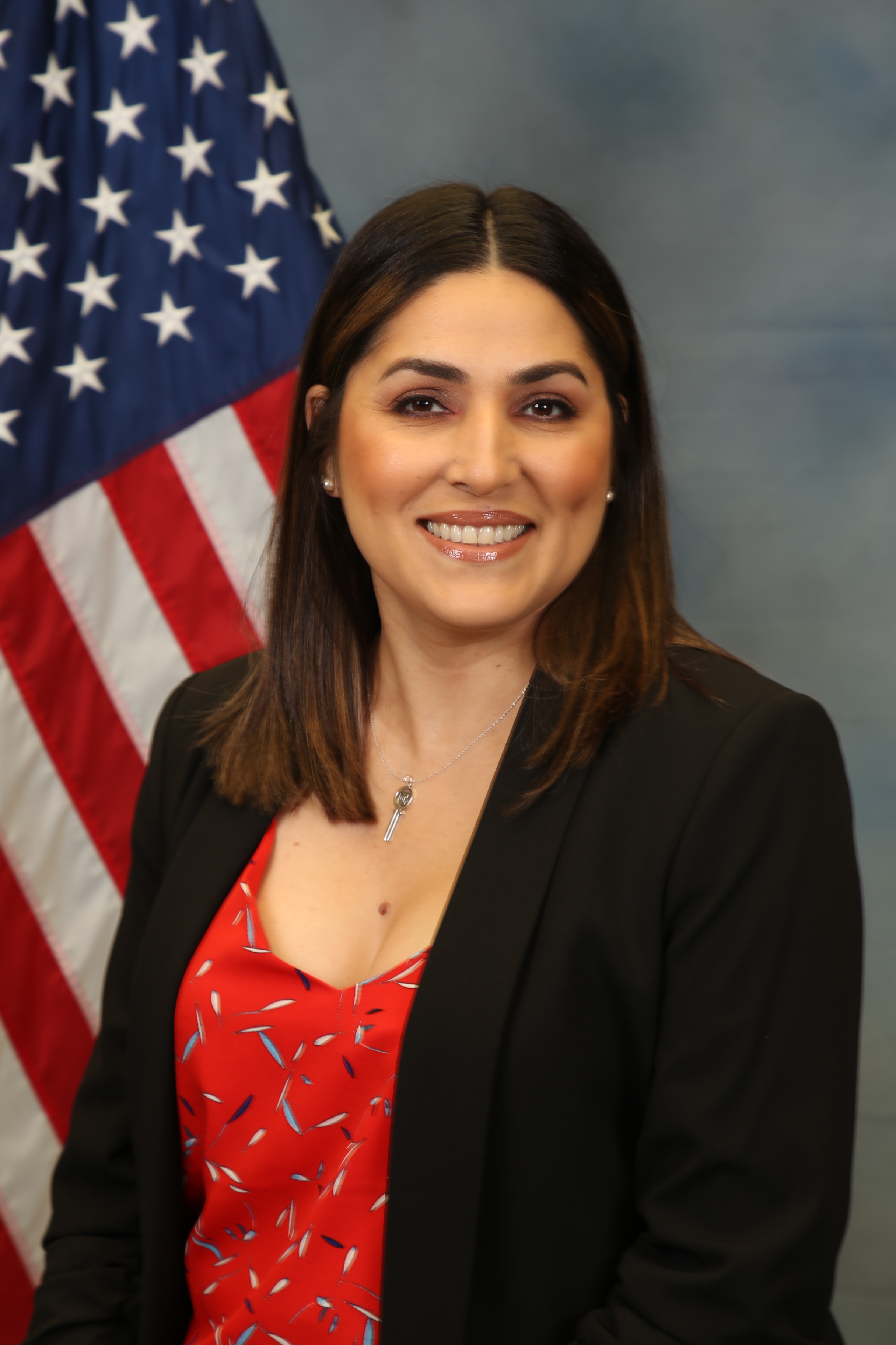 Photo of Brenda Delgadillo standing in front of the American flag.