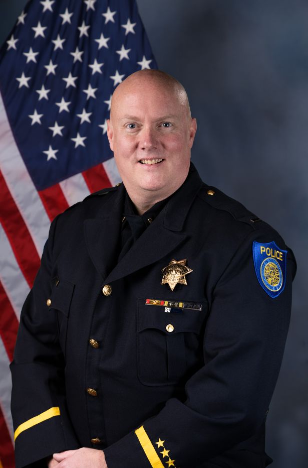Photo of Lieutenant Jon Houston in uniform standing in front of the American flag.